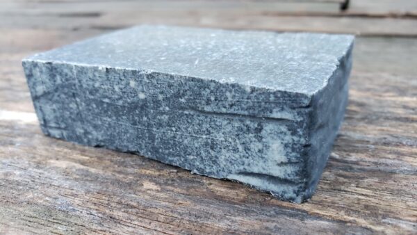 activated charcoal goat milk soap bar on a wood table